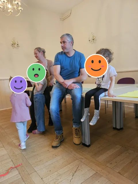 Familien beim Spielplatz-Café im Bürgerhaus; die Kinderköpfe sind mit Smileys verdeckt