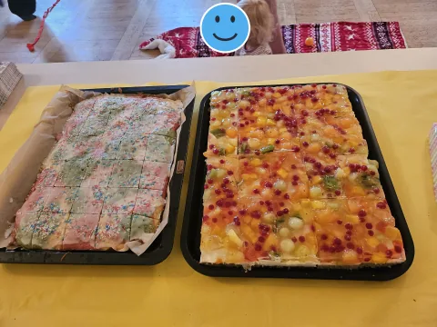 Bunte Kuchenbleche beim Spielplatz-Café; ein Kinderkopf im Hintergrund ist mit einem Smiley verdeckt