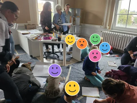 Kinder beim Malen und Basteln; die Kinderköpfe sind mit Smileys verdeckt