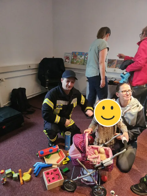 Spielecke mit Feuerwehr und Familie; der Kinderkopf ist mit einem Smiley verdeckt